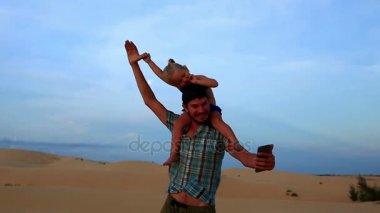 Babası taşıyan kız Selfie Dunes üzerinde yapar 