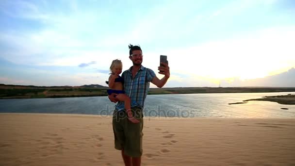 Отец держит девушку делает селфи на Дюне — стоковое видео