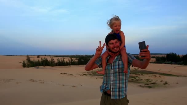 Père porte fille sur dune fait selfie — Video