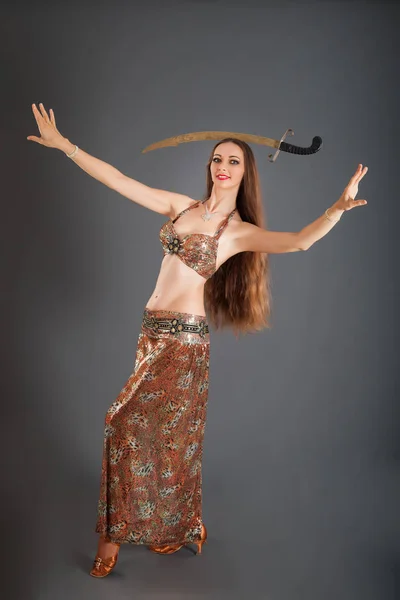 Tancerka brzucha porusza się z szablą na głowie w Studio — Zdjęcie stockowe