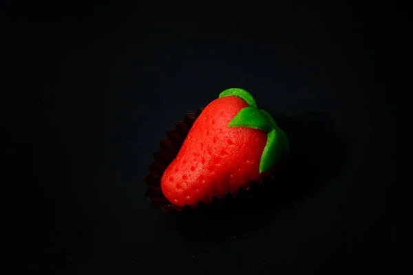 Одна красная клубника с конфетами в форме зеленого листа из марципана — стоковое фото