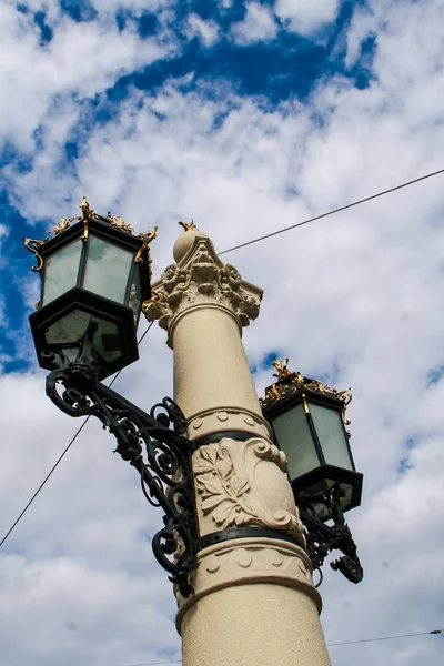 Eski Avrupa kentinde mavi gökyüzü ve beyaz Cumulus bulutlar karşı taş kutup üzerinde yaş-eski demir dantel şehir sokak ışığı