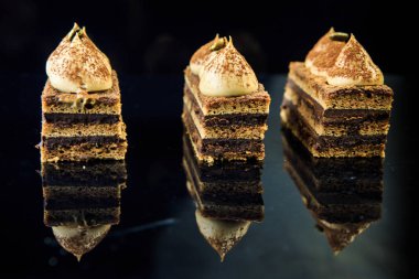 siyah ayna arka plan üzerinde beyaz krema ile dekore edilmiş dilimler lezzetli çikolata opera pasta