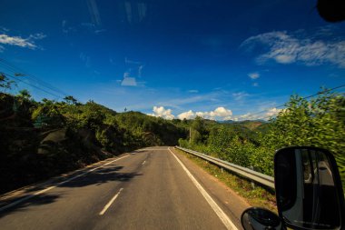 güneşli otoyol uzak tepeler ve mavi gökyüzü karşı yüksek tropik bitkiler arasında