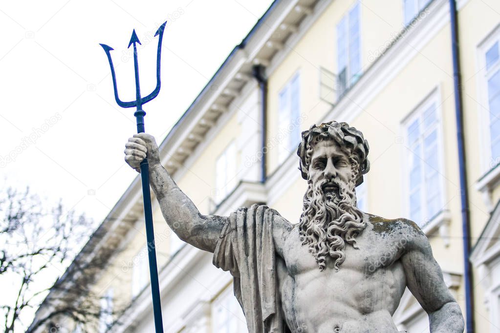 closeup city sculpture of Poseidon with three-pointed trident against building