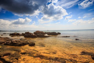 düz şeffaf sarı taşlı deniz alt gelgit karşı masmavi deniz ve mavi bulutlu gökyüzü altında