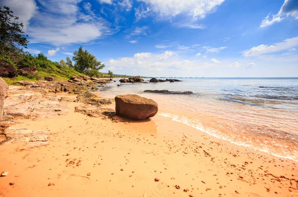 緑の斜面紺碧海青い曇り空を背景に低潮下の透明な水で砂のビーチで大規模なキューブ石 — ストック写真