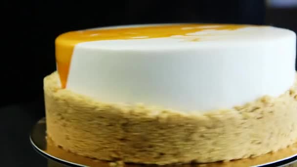在黑色背景上涂上白色和黄色釉面的亮白色麝香蛋糕围绕自己快速移动 — 图库视频影像