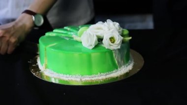 pudra eller şık sırlı yeşil musse pasta kesme dekore edilmiş beyaz çiçekler, Hindistan cevizi cips ve macaroons ile küçük parçalar halinde