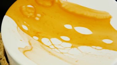 Üstten Görünüm yavaş yavaş siyah arka plan üzerine beyaz ve sarı sır ile kaplanmış parlak beyaz misk pastadan kendi etrafında makro taşır