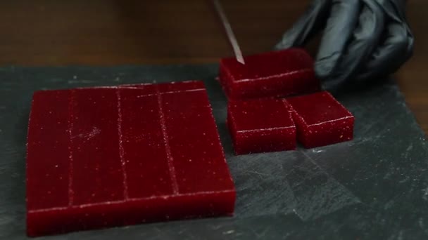 真紅の手作りマーマレードの大きな部分は 小さな断片に黒い石の背景カットでナイフで提供しています — ストック動画