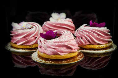 siyah ayna arka plan yansıması ile mor ve beyaz çiçekler dört pembe zephyr çerezleri süslenmiş