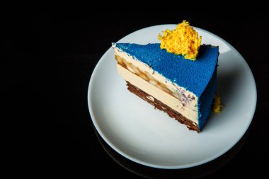 siyah arka plan üzerine beyaz plaka üzerinde mavi köpük pastasından en iyi ve karamel armut arası katman üzerinde sarı sünger kek dekorasyonu ile yan görünüm standları