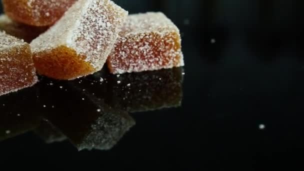 Große Gruppe Orangefarbener Marmeladenteile Mit Zucker Auf Schwarzem Spiegelhintergrund — Stockvideo