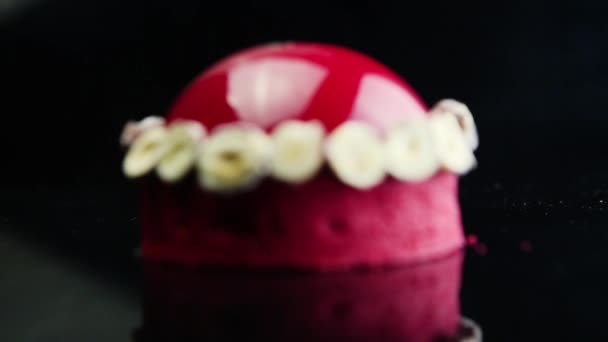 おいしい赤いムース デザート乾燥バナナで飾られ 鏡黒の背景に赤い釉薬でコーティングに焦点を当てる — ストック動画