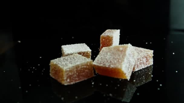 Marmeladenstück Fällt Auf Verstreute Orangefarbene Marmeladengruppe Mit Zucker Auf Schwarzem — Stockvideo