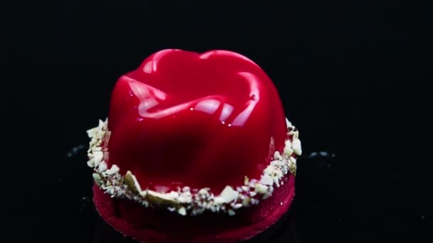 赤いムース デザート ココナッツ削りで飾られ 鏡黒の背景に赤い釉薬でコーティングにダウン クローズ アップ パノラマ — ストック動画