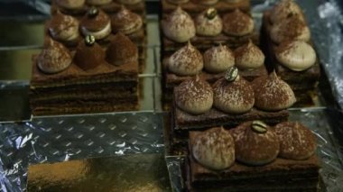 opera pasta dilimleri üzerinde metal arka plan hizmet beyaz krema ile dekore edilmiş yukarıda uzak siyah eldiven elinde alır