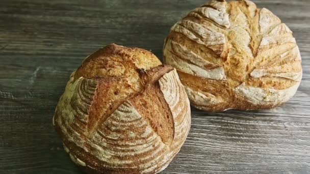 Ampliar a dos panes enteros de trigo redondo sobre una mesa de madera — Vídeo de stock