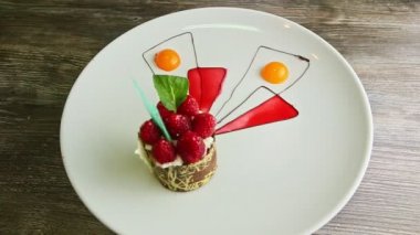 Güzel dekore edilmiş ahududu tatlısı beyaz tabakta dönüyor.