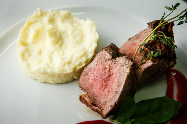 macro view on finely decorated baked meat pieces with potato puree