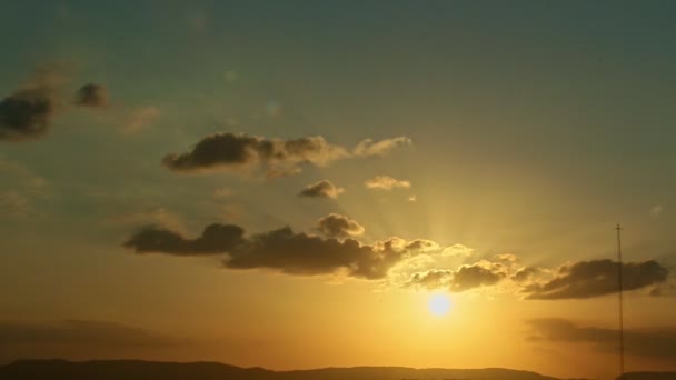 Donkere wolken varen langzaam op blauwe zonsondergang hemel met gouden stralen — Stockvideo