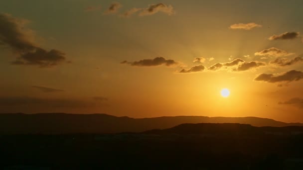 Sötét felhők lassan vitorláznak a naplemente égen kis sárga nappal és arany sugarakkal — Stock videók