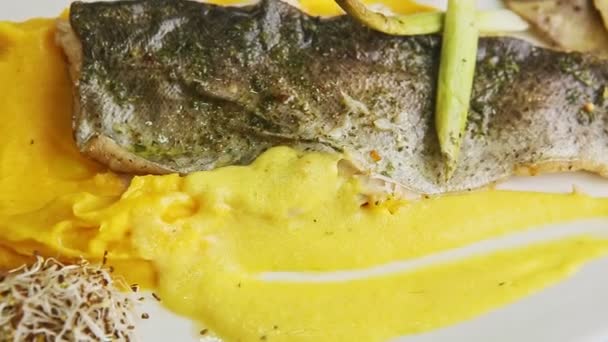 Vista dall'alto primo piano filetto di pesce fritto su purre di patate e verdure a fette ruota sul piatto — Video Stock