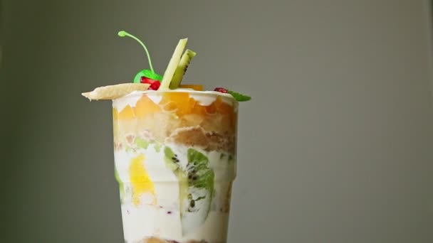 Nahaufnahme geschichtetes Fruchtcreme-Dessert in hohem Glas, das sich dreht — Stockvideo