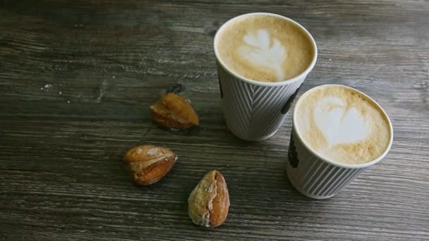 Concentrarse en dos tazas de café con leche y tres galletas de almendras — Vídeo de stock