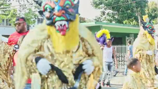 Homens em trajes de demônio dourado dançam no tradicional evento anual de carnaval dominicano — Vídeo de Stock