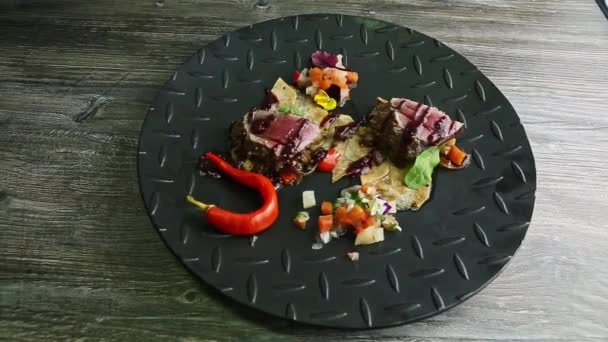 Вид сверху на куски мяса на гриле с картофельными чипсами и овощным салатом на черной тарелке — стоковое видео