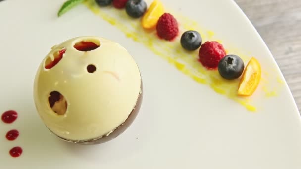 Zoom arrière de savoureux dessert en forme de boule de chocolat tourne sur plaque blanche — Video