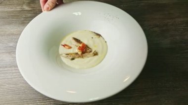 Karides ve kızarmış balık parçalarıyla süslenmiş lezzetli krema çorbasıyla tabağı döndürür.