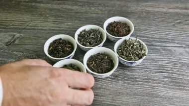 İnsan eli, çeşitli çay yapraklarıyla küçük tekneleri tek tek alıp götürür.