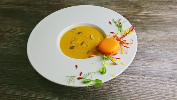 Sopa de crema de calabaza fresca con macaron naranja en un tazón blanco profundo — Vídeos de Stock