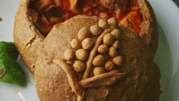 Top view closeup exquisite decorated fish soup in brown bread bowl on white plate — Stock Video