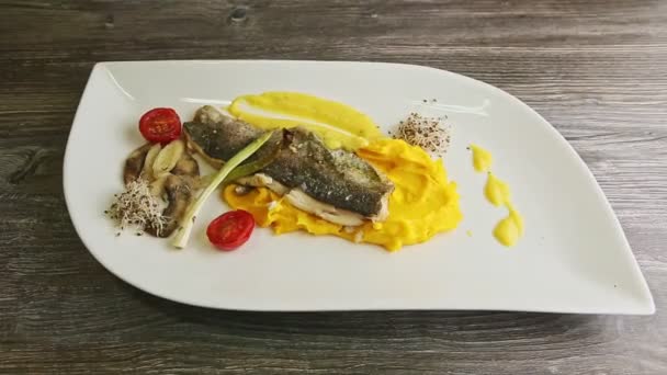 Vista superior sobre el filete de pescado de mar al horno con ronroneo de patata, verduras en rodajas y setas — Vídeo de stock