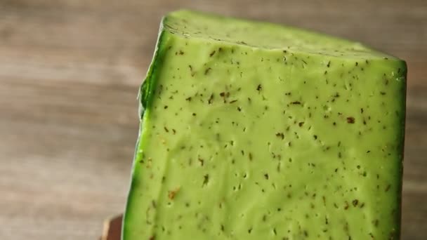 Zbliżenie duży kawałek zielonego sera z ziołami wirującymi wokół na małym talerzu — Wideo stockowe