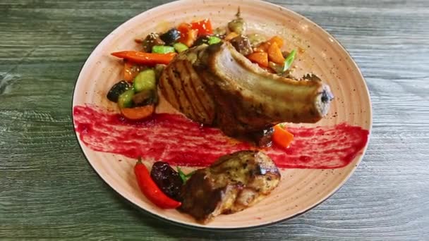 Πανόραμα σε μεγάλα τηγανητά παϊδάκια με κρέας και ψητά λαχανικά περιστρέφεται σε ροζ πιάτο — Αρχείο Βίντεο