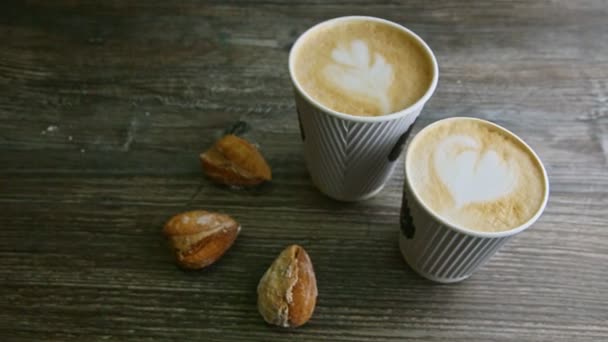 Puncak tampilan berfokus pada dua cangkir kopi susu dan tiga kue almond — Stok Video