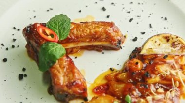 Yakın plan dekore edilmiş ızgara et kaburgaları beyaz tabakta döner.