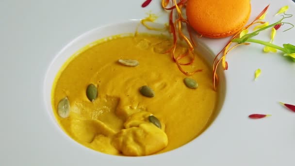Closeup μισοφαγωμένη σούπα κρέμα κολοκύθας με πορτοκάλι μακαρόν στο μπολ — Αρχείο Βίντεο