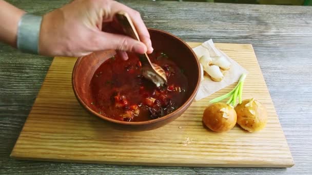 Manos humanas mezclan borscht tradicional y crema agria con cuchara de madera — Vídeos de Stock