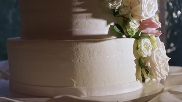 Панорама крупным планом на белом четырехъярусном торте с розовыми розами — стоковое видео