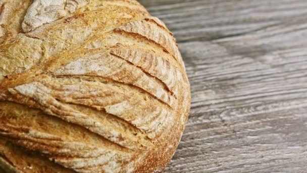 Nahaufnahme-Panorama eines ganzen runden Brotlaibs auf einem Holztisch — Stockvideo