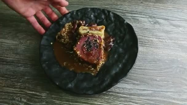 Menschenhand dreht schwarzen Teller mit trendig dekoriertem Fleischsteak — Stockvideo