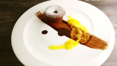 Zarif dekore edilmiş şeker tozlu küçük çikolatalı pasta çeşitli şuruplarla servis ediliyor. Modern beyaz restoran tabağında dönüyor.