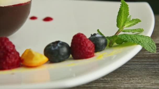 大观一排蓝莓 覆盆子 切碎的橙子和薄荷糖放在现代餐厅的白色餐盘上 旁边是巧克力球状甜点 — 图库视频影像