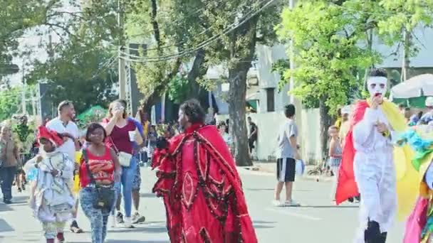 Personas con trajes brillantes caminan por la calle dominicana en el evento anual de carnaval — Vídeos de Stock